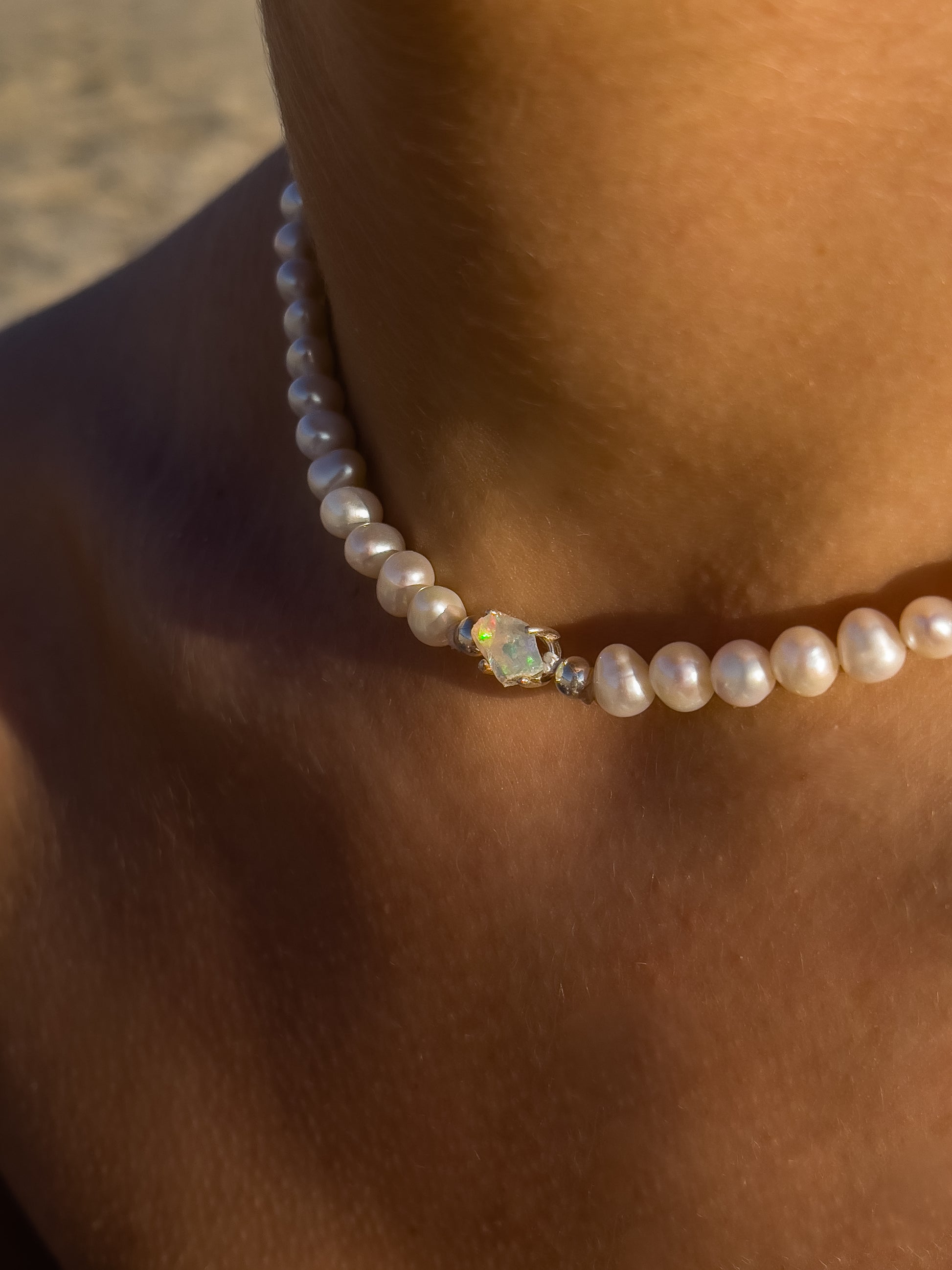 Pearl & Raw Opal Choker Necklace. Natural AA luxe pearls in a natural white are highlighted by the bright iridescent sparkle of Raw Australian Opal placed centrally on the clavicle, held in a sterling silver setting.  Personally and strung and knotted with 100% silk thread & handcrafted in Sterling Silver.   This necklace is a true statement piece.  Please note that this style is made to order, and due to the natural and raw elements, each piece is completely unique.